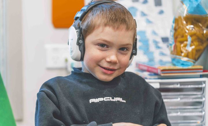 Student wearing headphones smiles during classroom activity